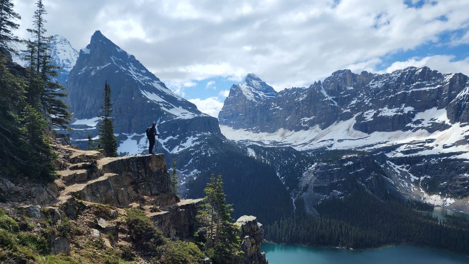 person standing on ridge in front of mountains